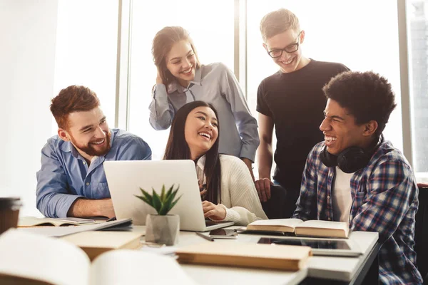 Concepto educativo. Los estudiantes positivos riendo, usando el ordenador portátil — Foto de Stock