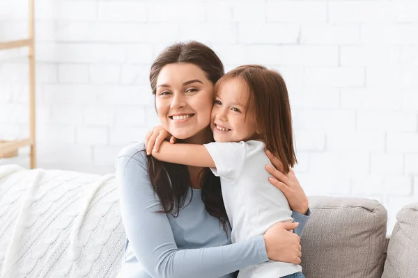 Retrato de madre alegre y pequeña hija abrazándose en casa —  Fotos de Stock