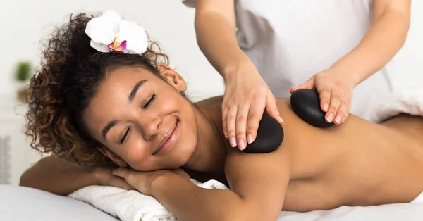 Розслаблена жінка отримує масаж рук гарячих каменів у спа-центрі — стокове фото