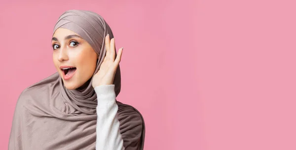 Curious muslim girl in hijab eavesdropping with hand near ear — Stock Photo, Image