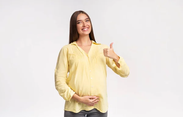 Joyful Pregnant Girl Gesturing Thumbs-Up Standing On White Studio Background — Stock Photo, Image