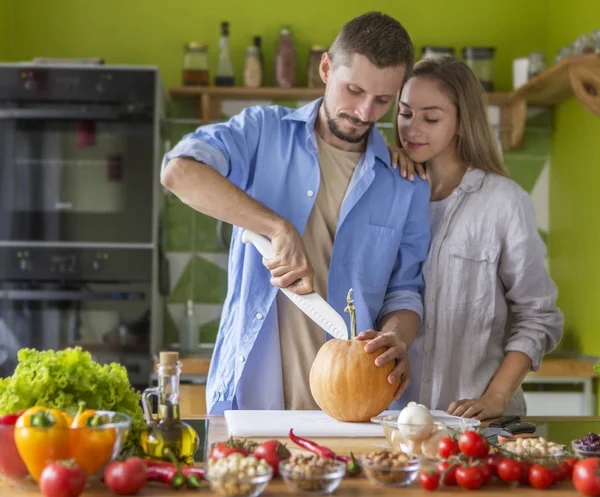 Feliz pareja joven haciendo pastel de calabaza juntos en la cocina — Foto de Stock