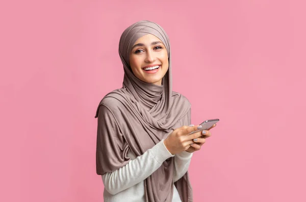Potret tersenyum muslim wanita di jilbab menggunakan smartphone — Stok Foto