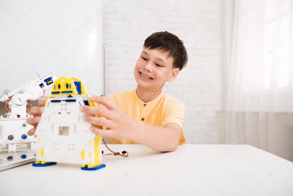 Happy schoolboy creating robot at lab, free space