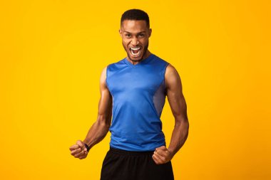 Heyecanlı siyahi adam stüdyoda zafer işaretini kutluyor.