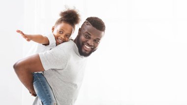 Black cheerful daddy holding his little daughter on his back clipart