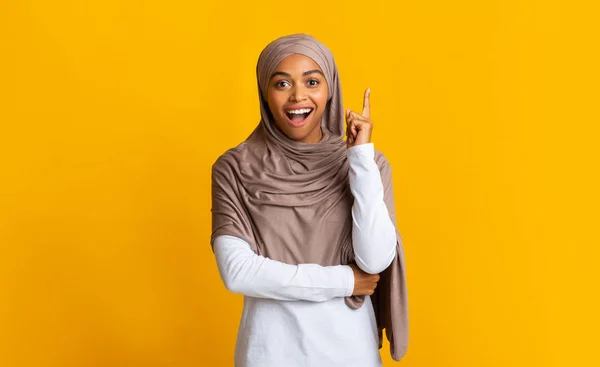 Молода жінка в хіджабі вказує пальцем вгору, маючи ідею — стокове фото