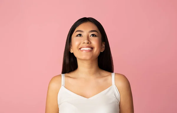 Olha para ela. Menina asiática feliz olhando para cima, fundo de estúdio rosa — Fotografia de Stock