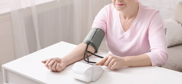 Mujer madura comprobando su presión arterial con tonómetro —  Fotos de Stock