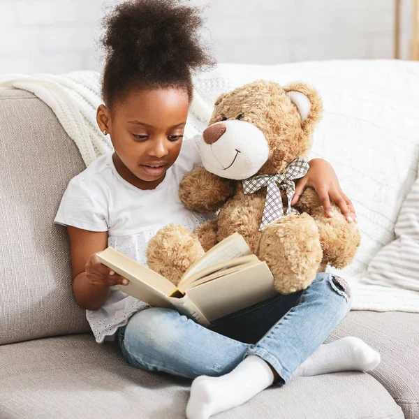 Adorable niño negro con libro de lectura de oso de peluche — Foto de Stock