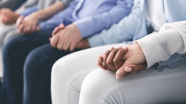 Closeup of unrecognizable people sitting in a row and holding hands — Stock Photo, Image