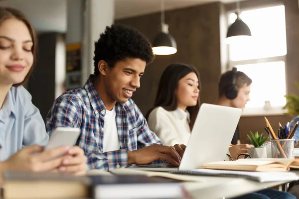 Inteligentny afro facet studiuje z laptopem i książkami w bibliotece — Zdjęcie stockowe