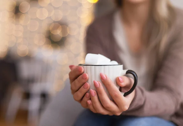 Mulher aquecendo as mãos com xícara de cacau com marshmallows — Fotografia de Stock