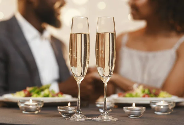 Two glasses of champagne over cuddling black couple — 스톡 사진