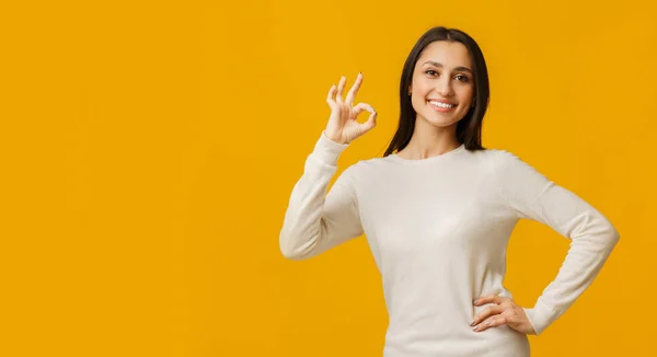 Optimistic millennial girl showing ok gesture while posing over yellow background — Stock Photo, Image