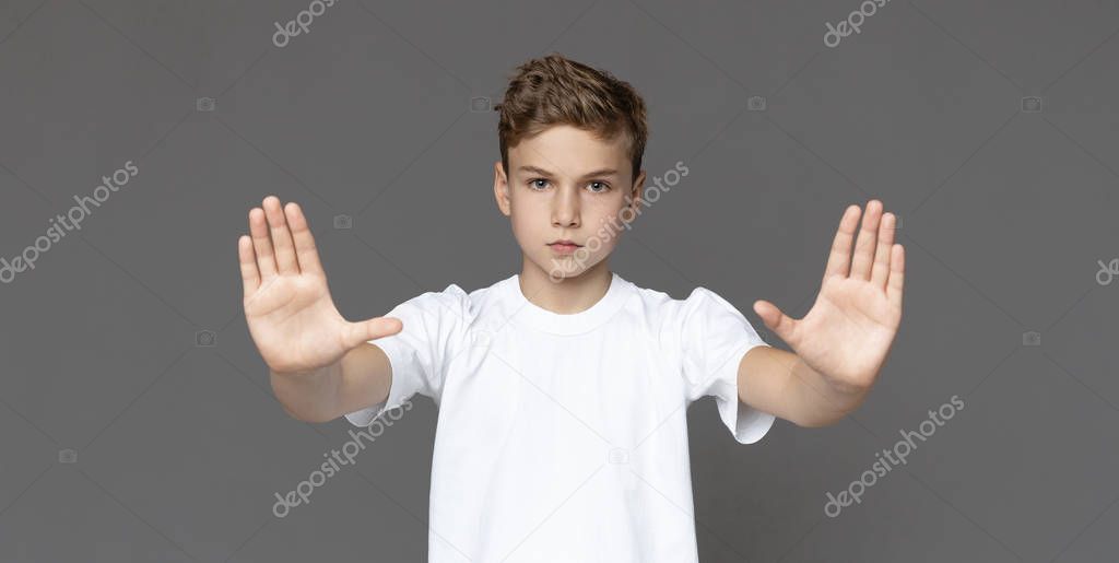 Teenage boy making stop gesture over grey background