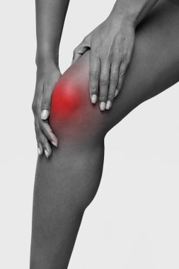 Monochrome cropped photo of afro woman massaging her injured knee