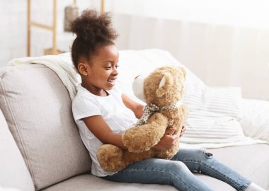 Beautiful afro girl holding big toy teddy bear