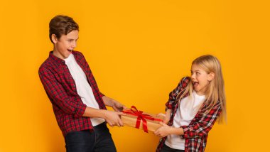 Little brother and sister fighting for gift, pulling present box clipart