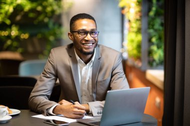 Black business guy taking notes in notebook