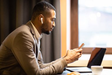 Portrait of black guy using cell phone and computer