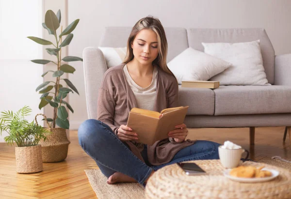 Ragazza pacifica che legge un libro. godendo il caffè sul pavimento — Foto Stock