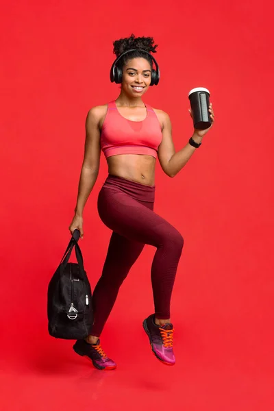 Garota fitness animado com fones de ouvido correndo alegremente para ginásio — Fotografia de Stock