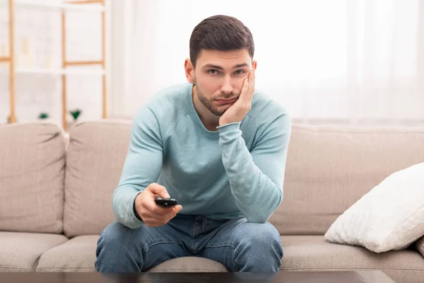 Aburrido chico cambiar de canal viendo la televisión sentado en el sofá interior — Foto de Stock