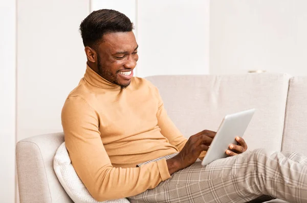 Happy Guy met behulp van Tablet Computer Zittend op de bank thuis — Stockfoto