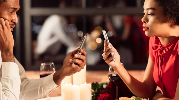 Znudzona para korzystająca ze smartfonów na romantycznej kolacji w restauracji, Panorama — Zdjęcie stockowe