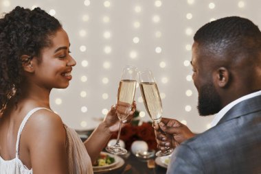 Back view of black young couple drinking champagne in restaurant