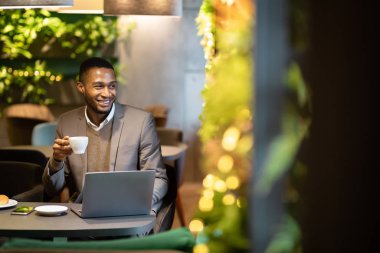 Black guy drinking tea and using personal computer