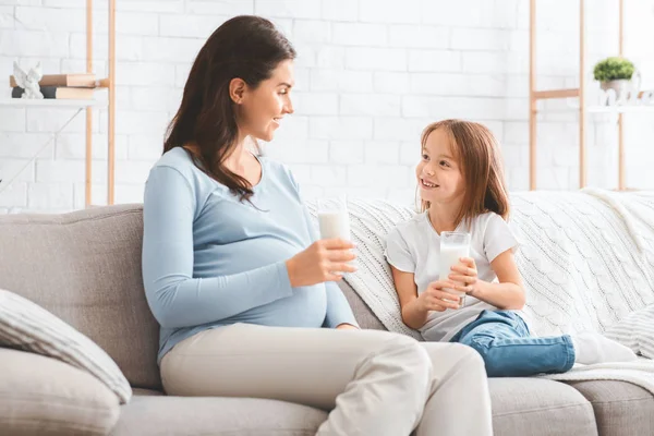 Pregnant loving mom drinking milk with her sweet daughter — Stok fotoğraf