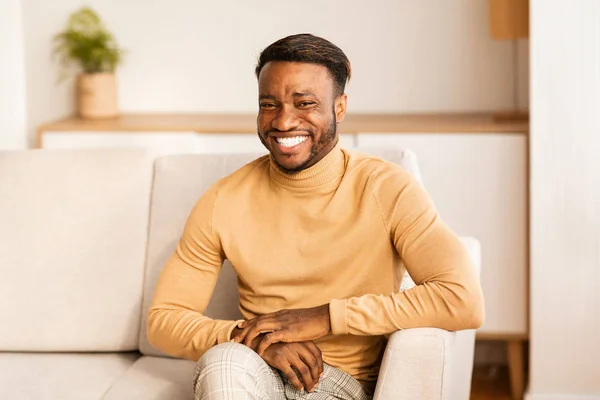 Feliz hombre afroamericano sonriendo sentado en el sofá en casa — Foto de Stock