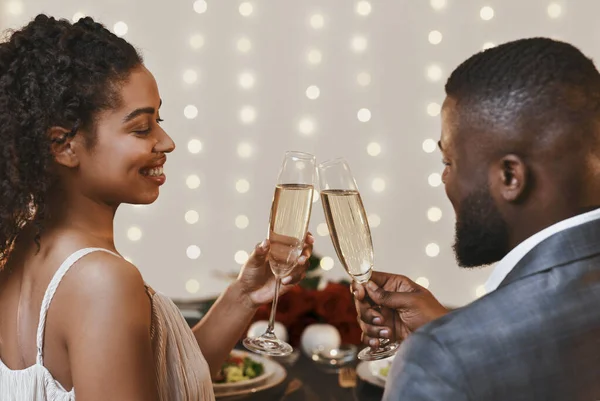 Achteraanzicht van zwart jong stel drinken champagne in restaurant — Stockfoto