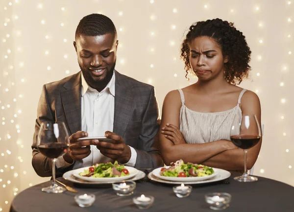 Wkurzona kobieta patrząc na swojego mężczyznę za pomocą telefonu podczas randkowania — Zdjęcie stockowe