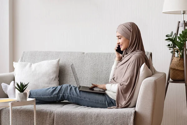 Perempuan Arab dalam hijab menggunakan ponsel dan laptop di rumah — Stok Foto