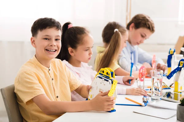 Gelukkig schooljongen tonen zijn robot en glimlachen bij stam les — Stockfoto