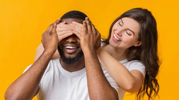 Игривая молодая женщина закрывает глаза своим парням сзади, удивляя его — стоковое фото