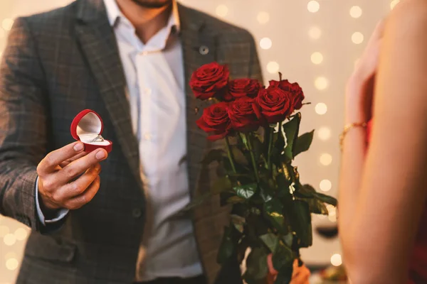 Homem romântico com anel de noivado e flores propondo namorada para se casar — Fotografia de Stock