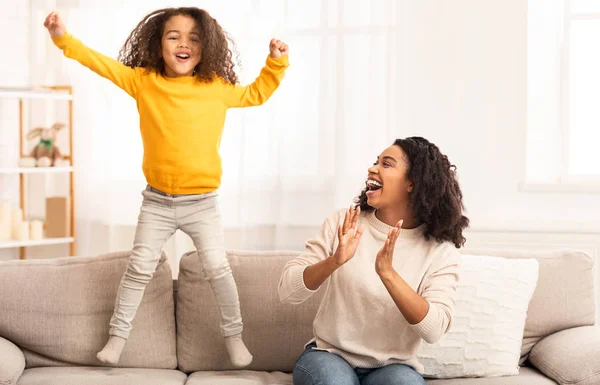Mãe e filha se divertindo pulando no sofá em casa — Fotografia de Stock