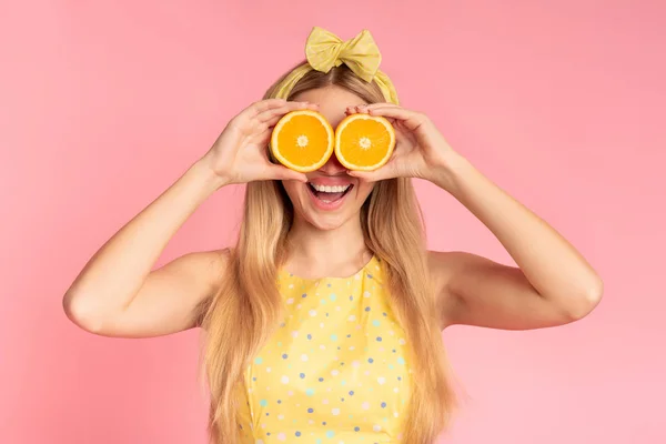 Menina loira segurando fatias de laranja ao lado dos olhos — Fotografia de Stock