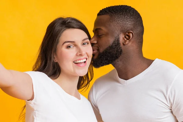 Romantic multiracial couple taking selfie, loving black guy kissing his girlfriend — 스톡 사진