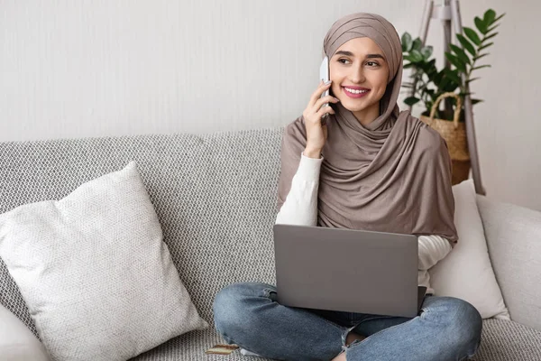 Gadis Islam menggunakan laptop dan berbicara pada ponsel di rumah — Stok Foto