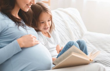 Küçük heyecanlı kızın annemle kitap okumasını kapat.