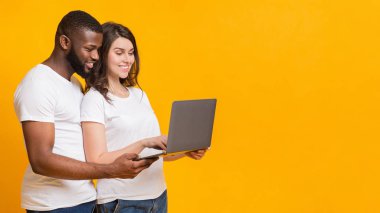 Dizüstü bilgisayar kullanan ve bilgisayar ekranına birlikte bakan mutlu bir çift.