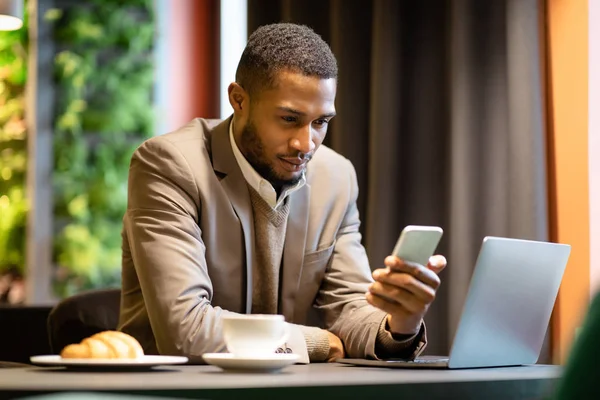Retrato del afro ocupado usando teléfono celular y computadora —  Fotos de Stock