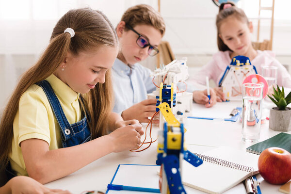 Schoolgirl making robot, working with wires in class