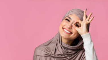 Türbanlı mutlu Arap kız kameraya iyi bir hareketle bakıyor.