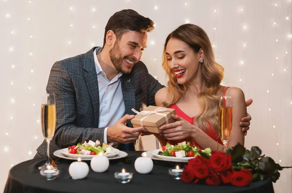 Homem amoroso namorada surpreendente com presente romântico no jantar no restaurante — Fotografia de Stock